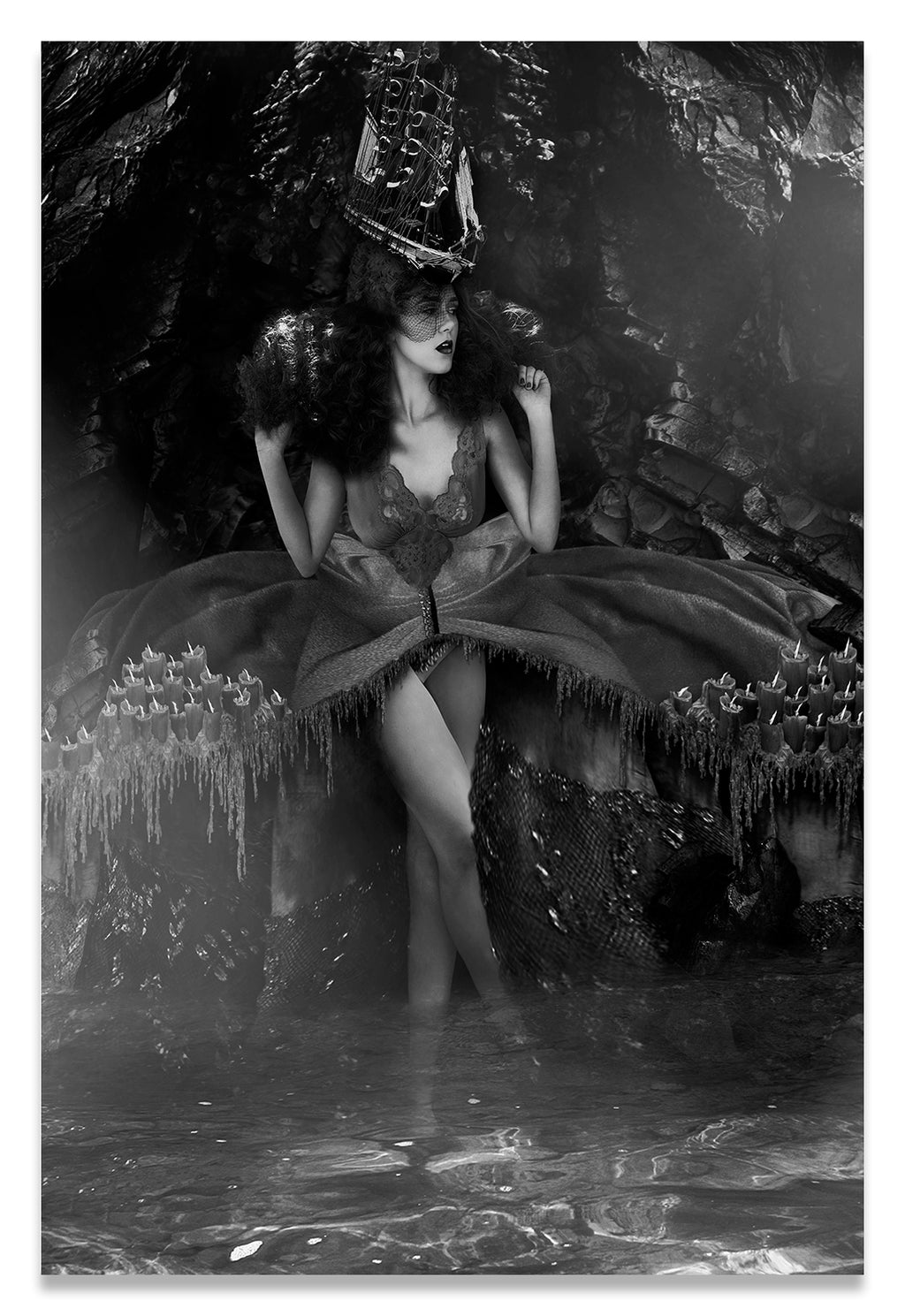 Vertical Black and White Portrait of a Woman Standing in Water in Purgatory; adorned with a Ship Hat and Melted Candles Along Her Dress.