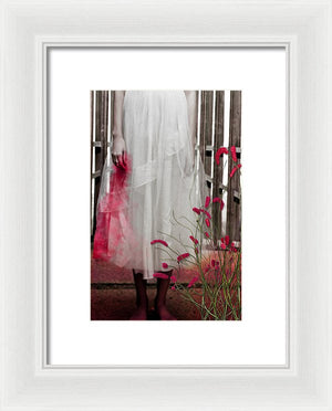 Woman in a Vintage White Lace Dress, cropped at waist, Standing With a Bloody Hand Dripping Down Her Dress in front of a Gate-Framed Print